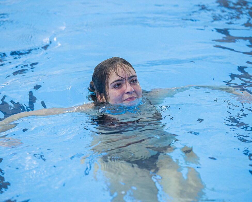 Pige, der svømmer i svømmebassin